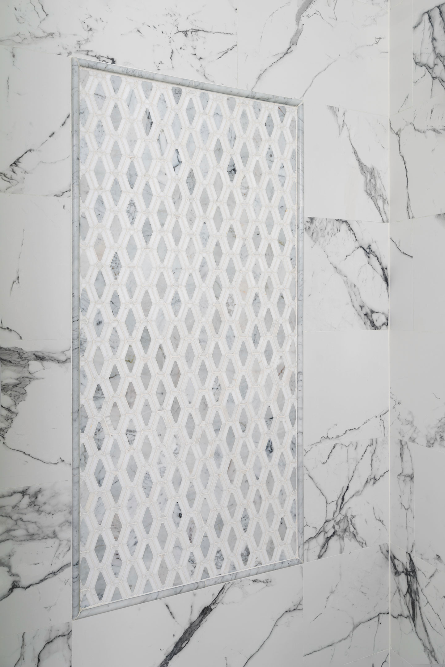 The image shows a close-up view of a modern wall-mounted mirror with a geometric pattern design, set against a marble backdrop with a grayish hue.