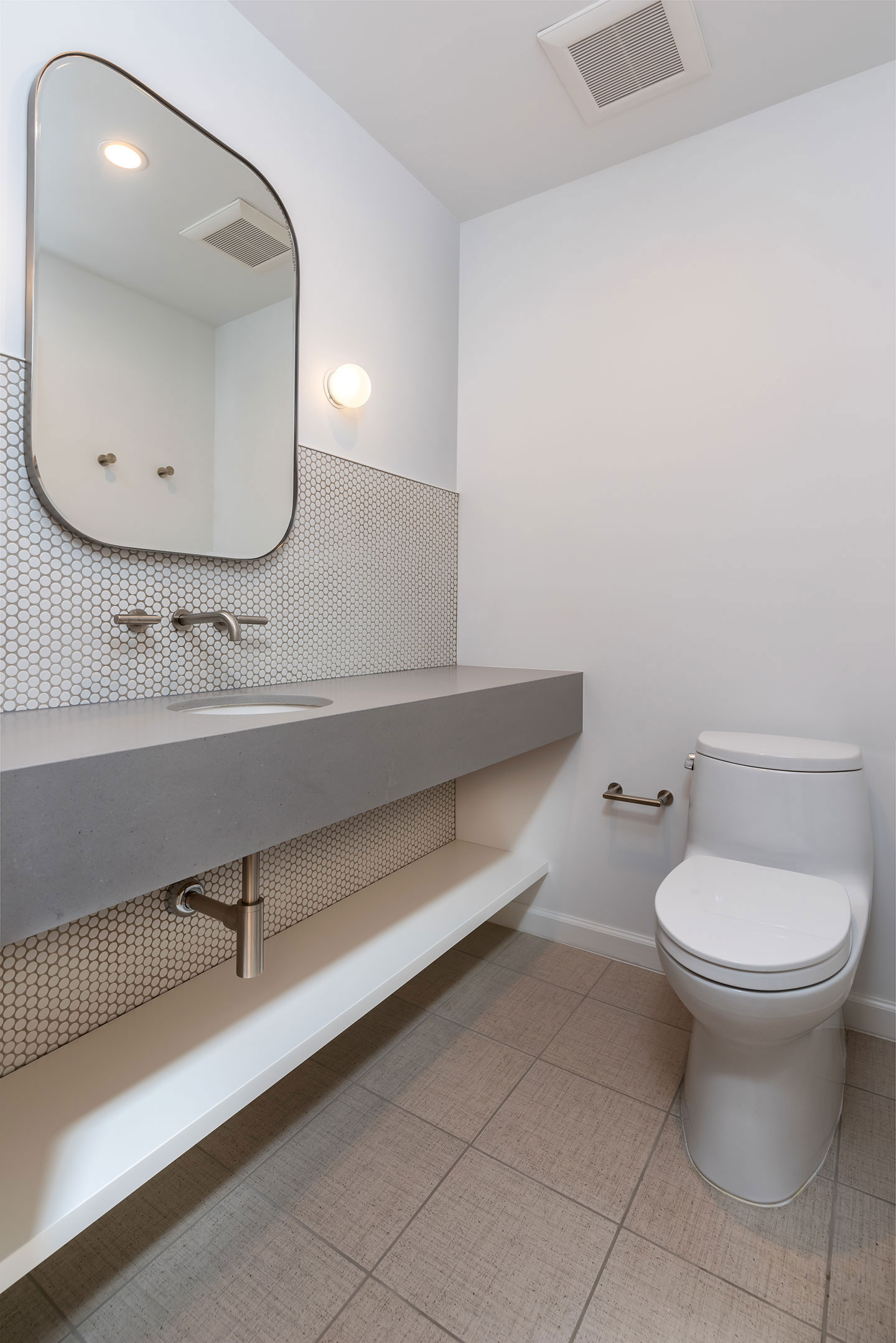 The image shows a modern bathroom with a white tiled floor, a silver sink vanity, a toilet, and a mirror above the sink.
