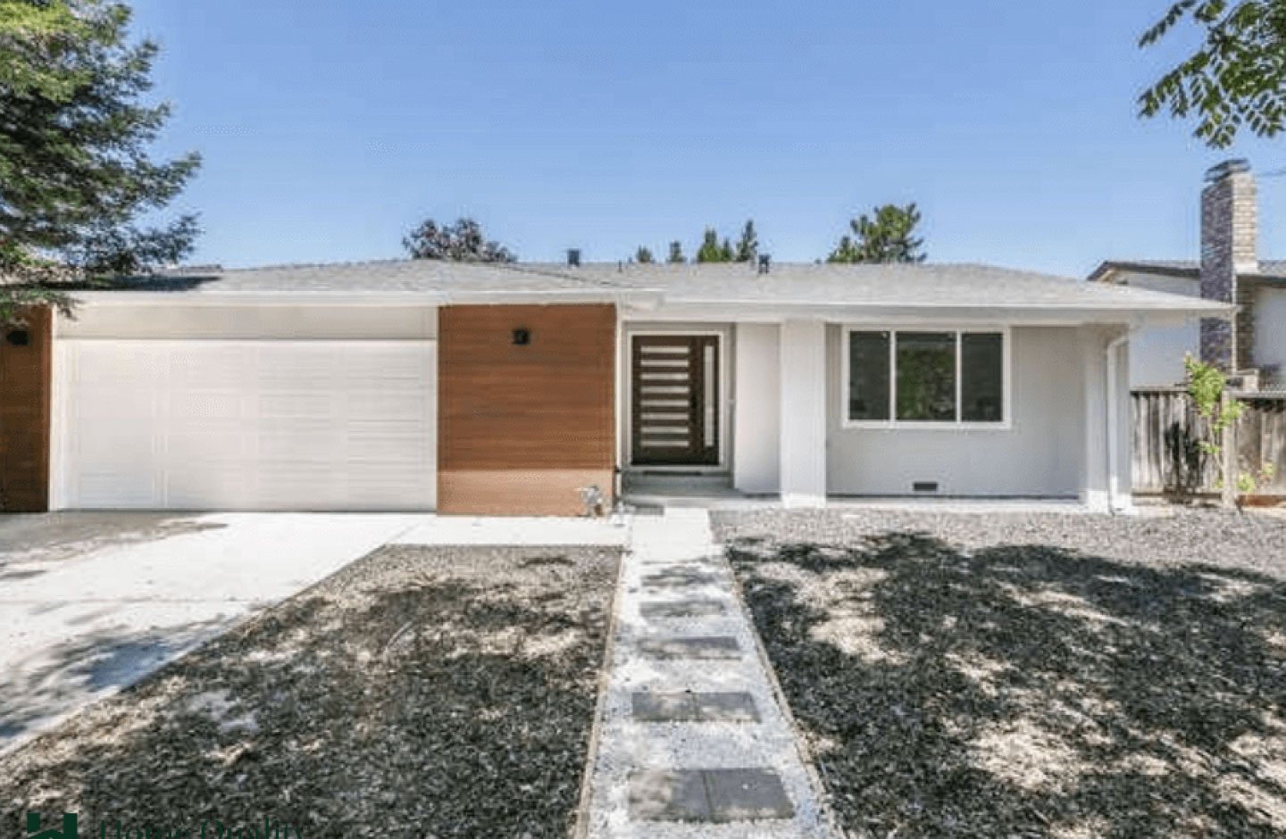 A modern single-family house with a garage door partially open, situated on a suburban street with a clear sky.
