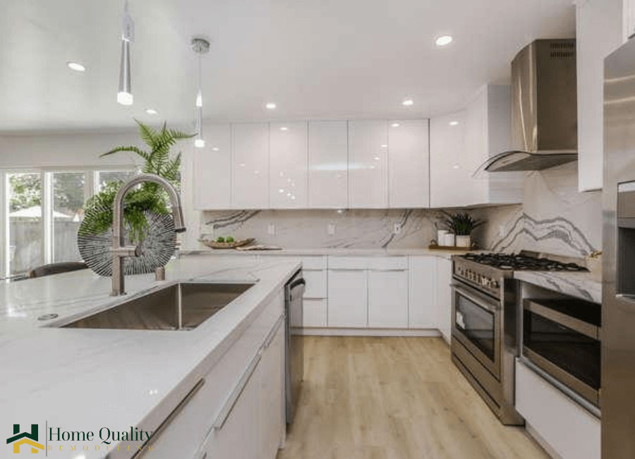 A modern kitchen with clean lines, white cabinets, stainless steel appliances, a marble countertop, and a spacious island with a sink.