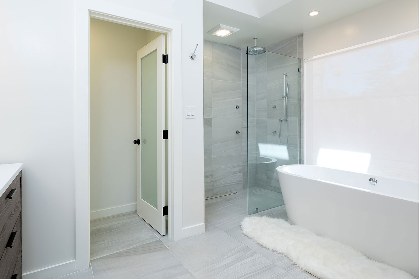 The image depicts a modern bathroom with a walk-in shower, bathtub, and white fixtures.
