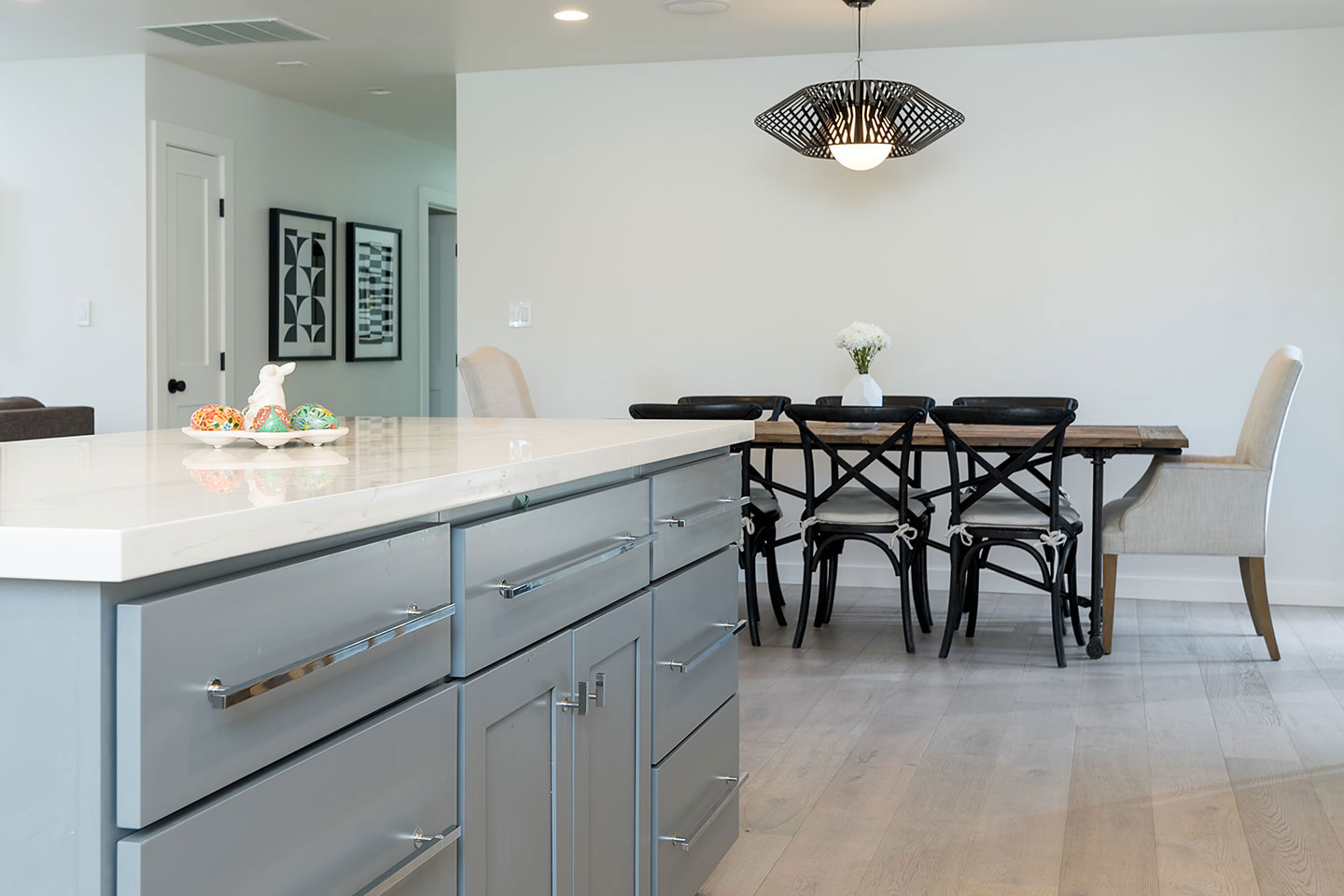 A modern kitchen with stainless steel appliances, a large island, and a dining table set for four.