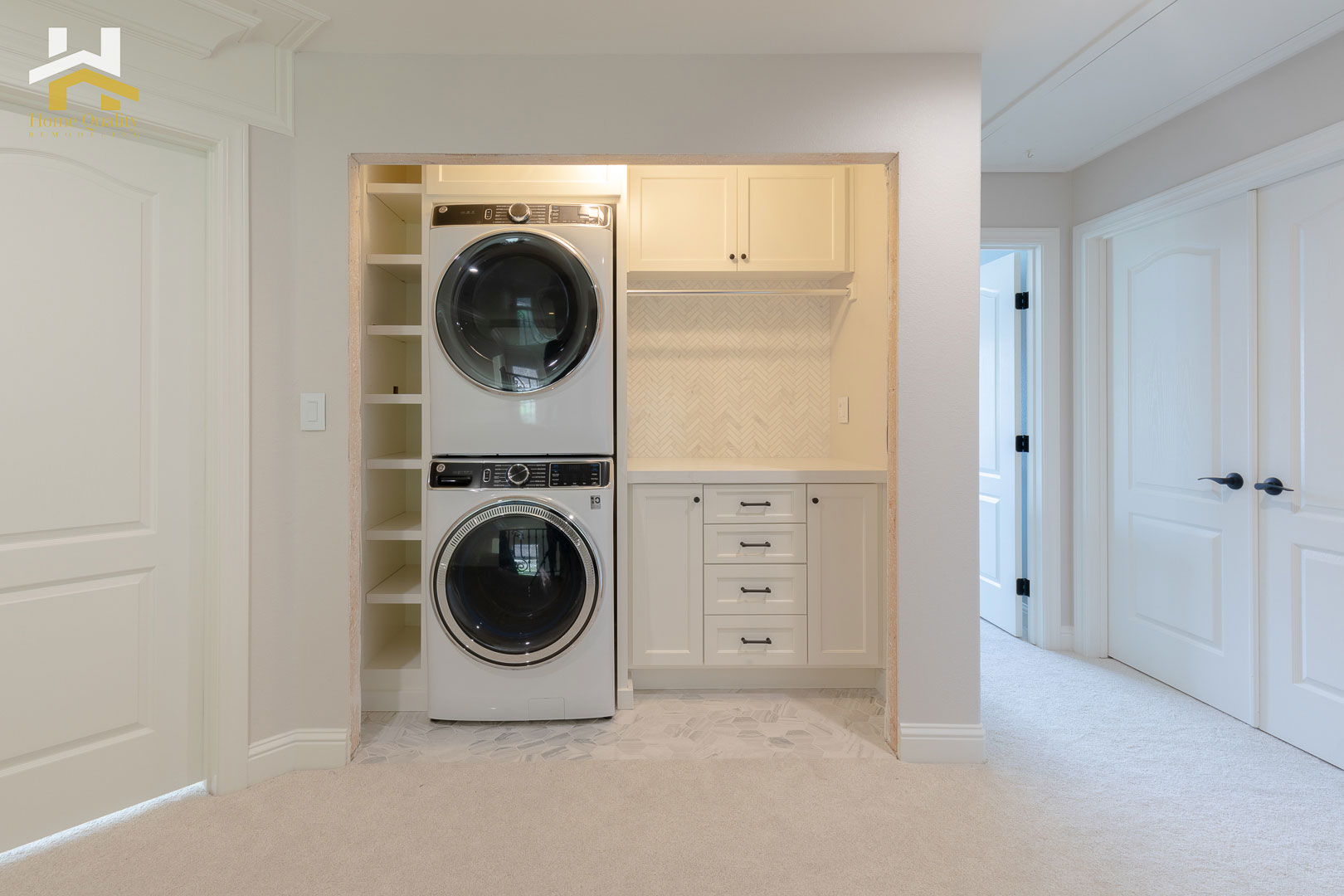 The image depicts a modern laundry room with two white washing machines, a tall stacked laundry basket, and a shelving unit for storage.