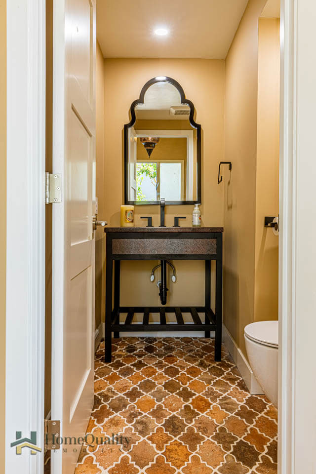 The image shows a bathroom interior with a sink vanity, mirror, and a patterned floor.