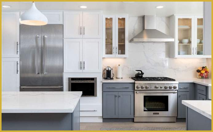 The image shows a modern kitchen interior with white cabinets, stainless steel appliances including a refrigerator, oven, and microwave, a marble countertop, a large island with a sink, a backsplash, pendant lighting above the island, and a wooden floor.