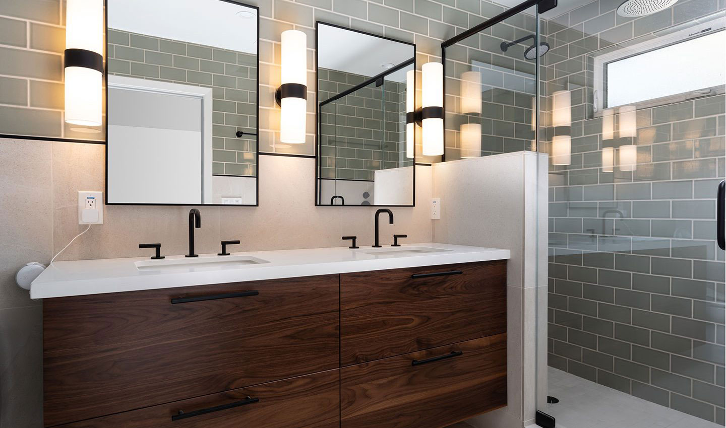 A modern bathroom with a double sink vanity, large mirror, and tiled walls.